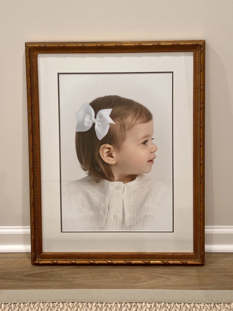 Gold Custom frame of a one Year old girl in an heirloom portrait with white bow in her hair 