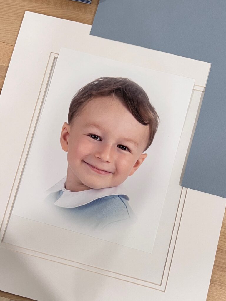 picture of a photographic print of an heirloom portrait laying on a table with blue mat board corner, showing the preparation to create a custom frame