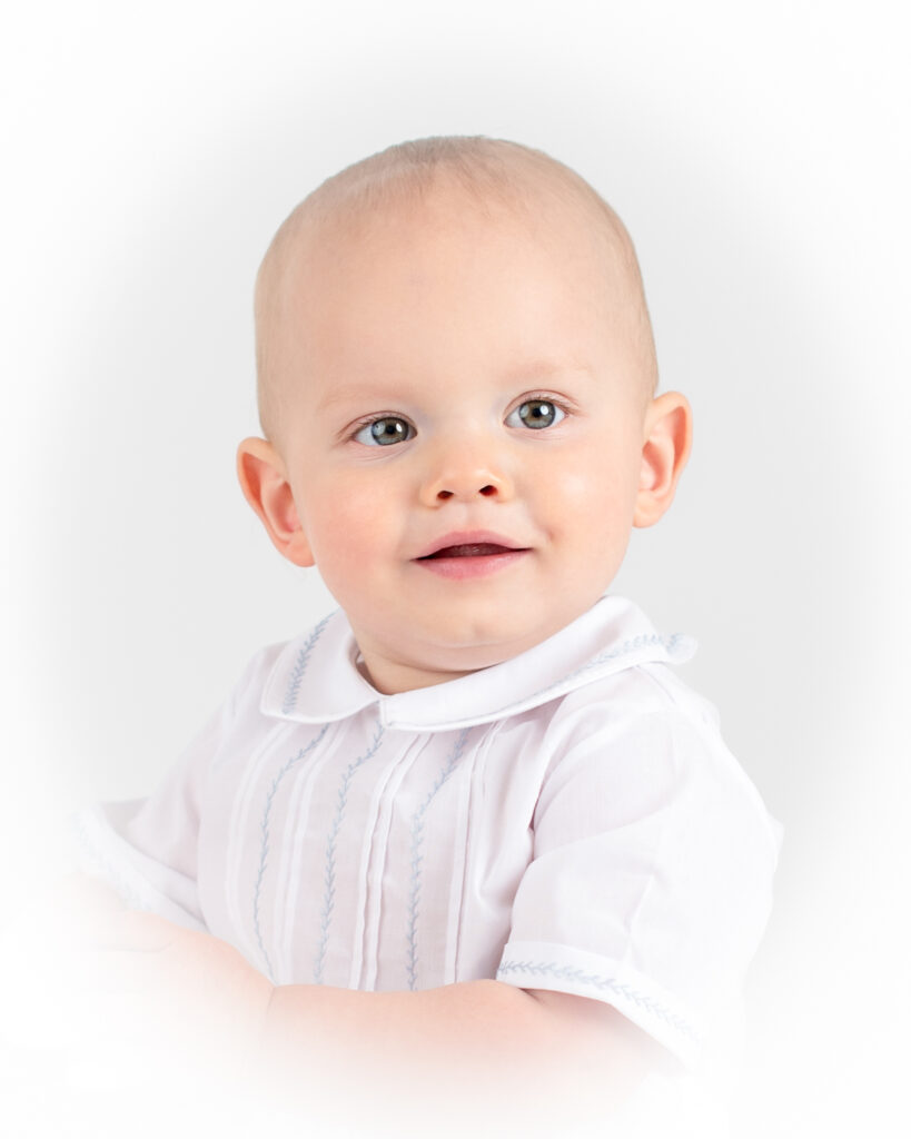 Heirloom portrait of a baby boy looking off to the side and wearing beautiful hand embroidered clothes